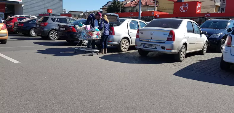 Un cuplu își încarcă cumpărăturile în mașină, în parcare la Kaufland