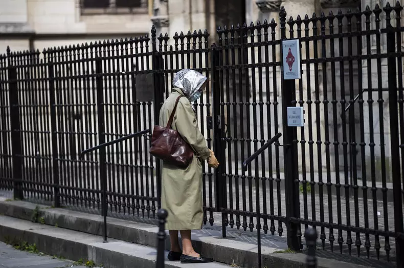 O femeie se roagă în fața unei biserici închise din Paris