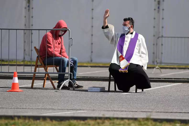 În parcarea unei biserici din Varșovia, un preot îi spovedește pe credincioși