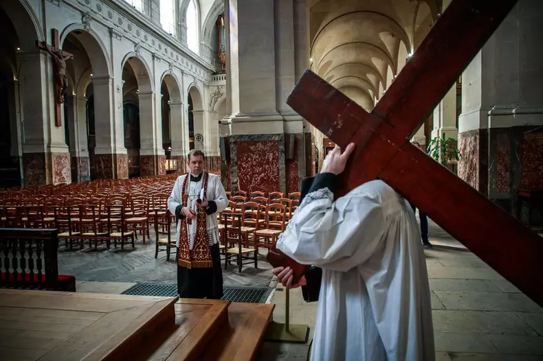 Un preot din Paris cară o cruce într-o biserică goală, pentru procesiunea Calea Sfintei Cruci. Și în Franța bisericile au fost închise