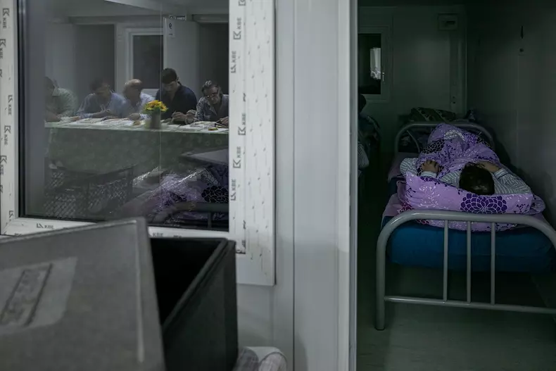 În timp ce unii oameni care au intrat mai devreme în adăpost deja dorm, alții sunt la duș, mănâncă sau încă sunt afară și așteaptă să le vină rândul pentru a intra în adăpost.