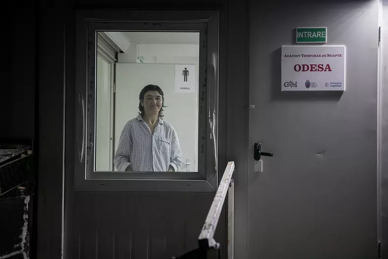 Pentru că afară sunt temperaturi sub zero grade, o femeie care ar vrea să vadă artificiile de la miezul nopții rămâne totuși în adăpost și așteaptă artificiile la geam.