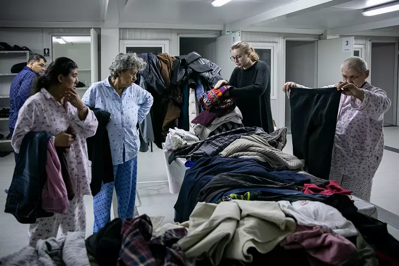 Cei de la Carusel le oferă haine groase beneficiarilor înainte să plece din adăpost.