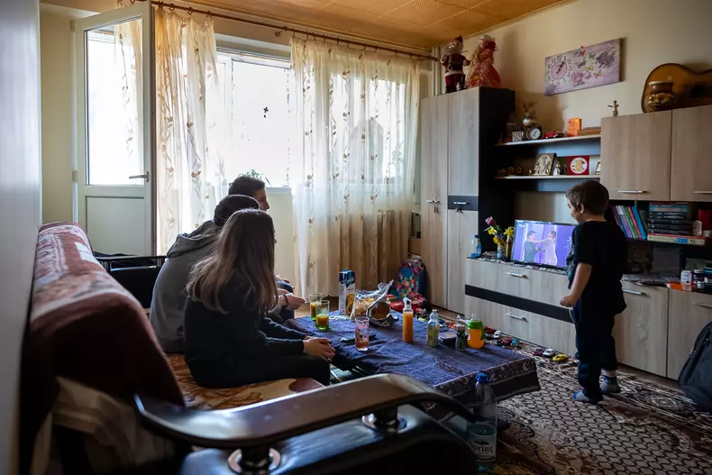 Mihai, Ionuț și Irina se uită la un film pentru copii, în timp ce Andrei aleargă, plin de energie, prin casă.