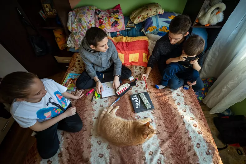 Irina, Ionuț, Mihai și Andrei stau în pat împreună cu motanul Bubu.