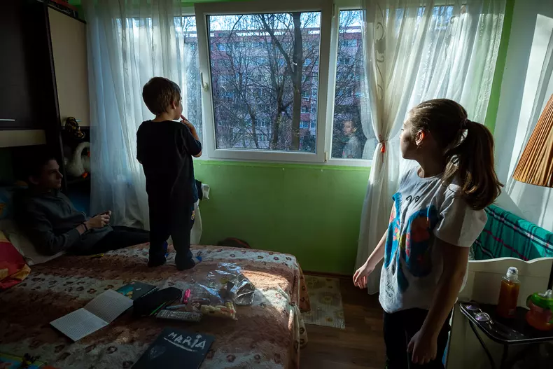 După ce au pus semințe pe pervaz, Andrei și Irina așteaptă să vină porumbeii să le mănânce.