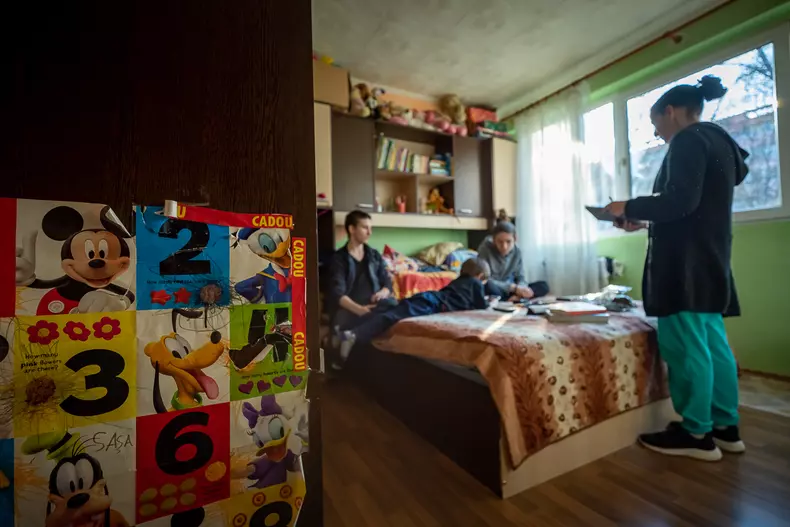 Ajutați de mama lor, copiii se pregătesc să își facă temele primite de la profesorii lor peste zi.