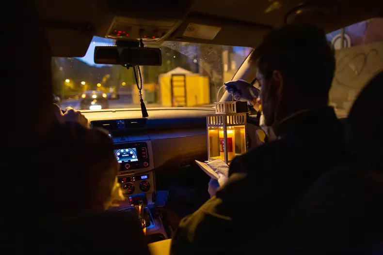 Preotul Daniel Roșu verifică lista cu enoriașii care au solicitat Lumina Sfântă în noaptea de Înviere, in mașina unui voluntar al bisericii Sfânta Treime Dudești. Foto Vlad Chirea