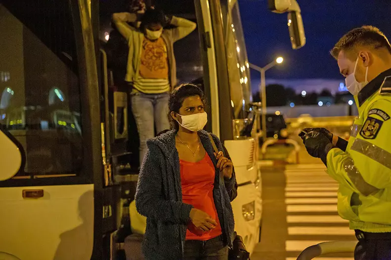 Un polițist le verifică permisele de muncă muncitorilor din Sri Lanka