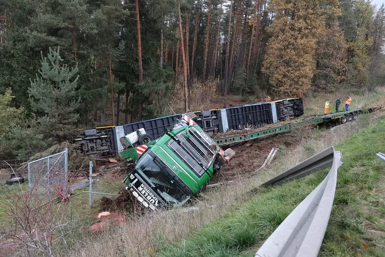 Heavy transporter with streetcar slides down embankment