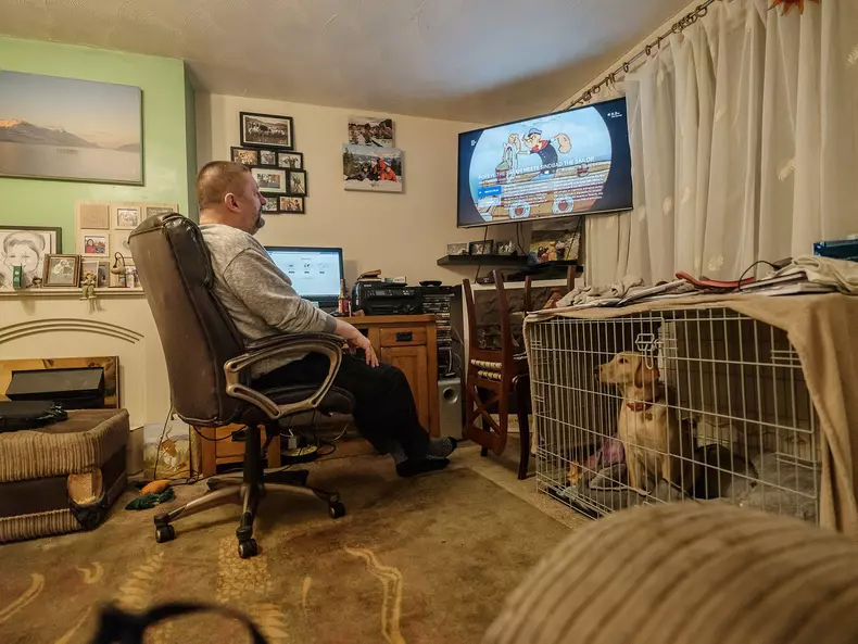 Cătălin se uită la TV în livingul familiei din Rugby, UK