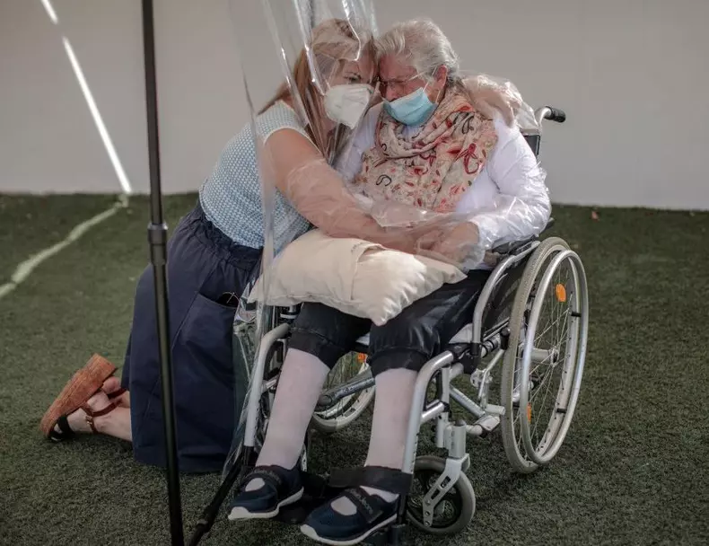 Relatives embrace through plastic device