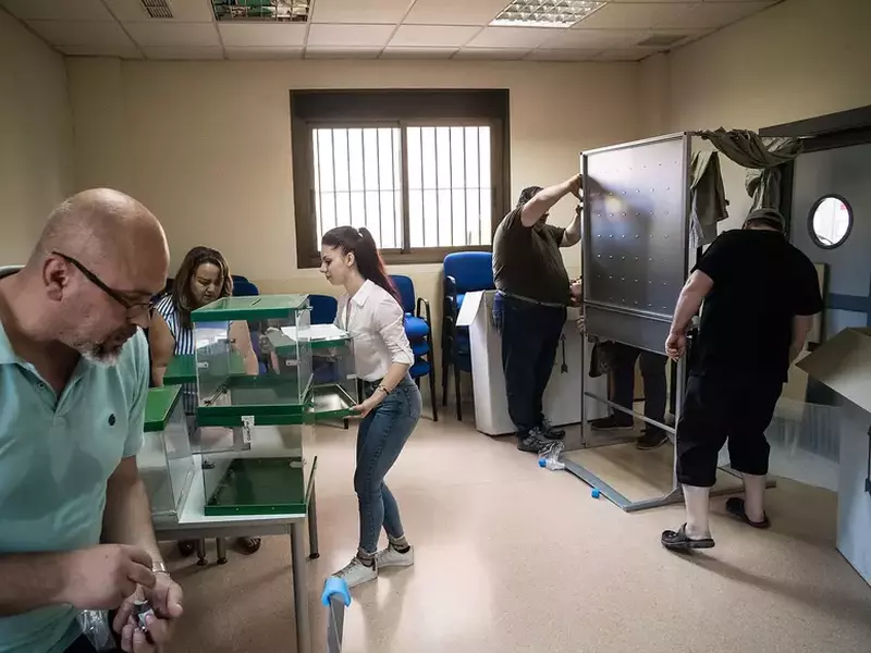 Membrii secției de votare din Roquetas de Mar asamblează cabinele de vot cu o zi înainte de alegeri.