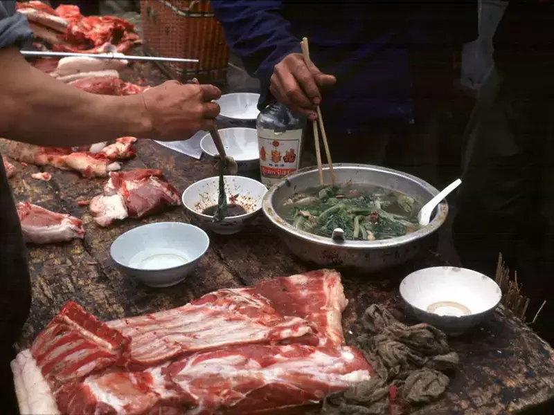 Piață ilegală de animale în Wuhan, China. Vânzătorii mănâncă pe tarabă lângă carcasele de animale scoase la vânzare