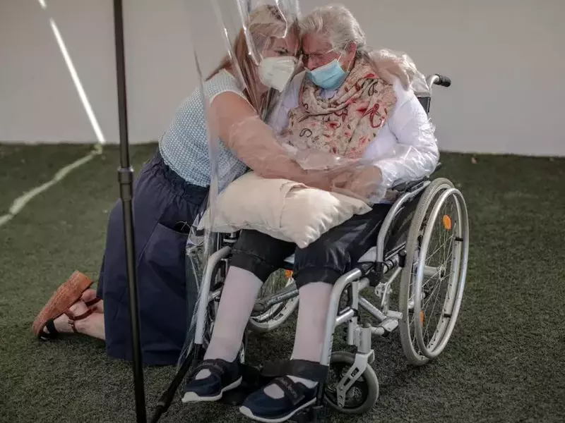 O femeie își îmbrățișează mama, cu ajutorul unei folii din plastic, la un cămin de bătrâni din Valencia FOTO: EPA