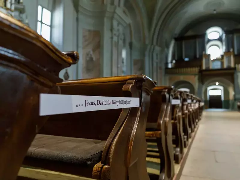 Plăcuțe cu versete din Biblie puse pe anumite rânduri de bănci, pentru ca pelerinii să păstreze distanța