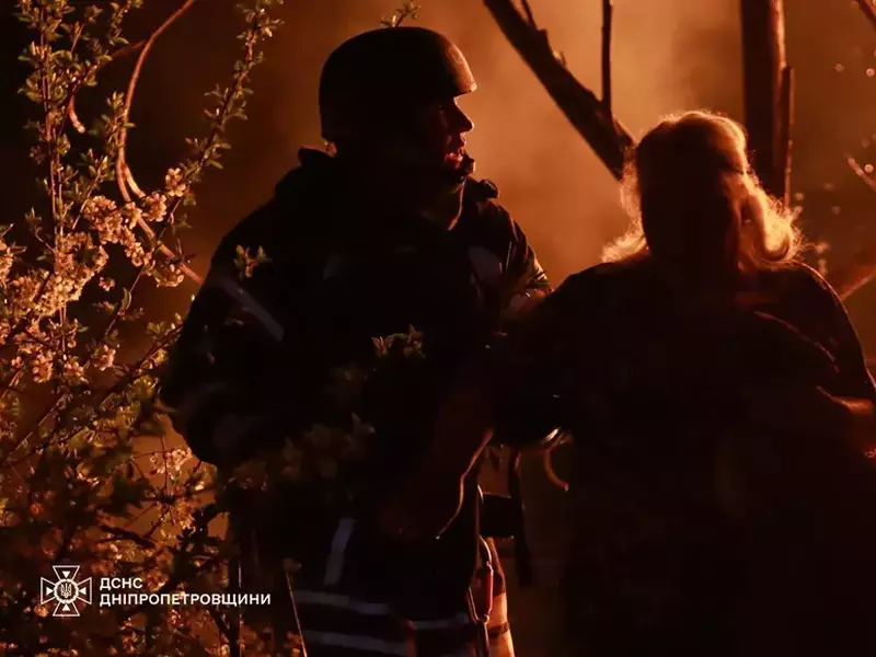 Un salvator ucrainean stî lângă o femeie și privesc flăcările care au cuprins o clădire, în urma atacului lansat de ruși în Dnipro
