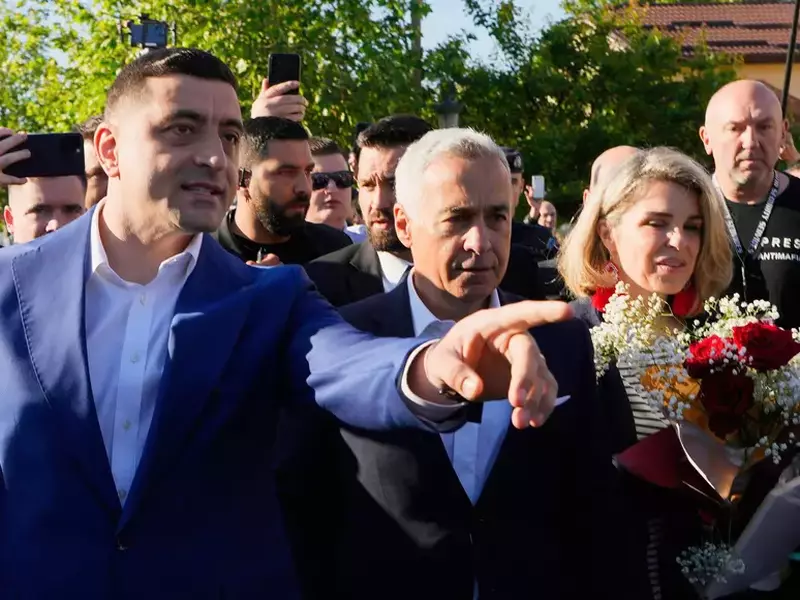 Geoge Simion arată cu mâna stângă spre cineva. Lângă el se află Călin Georgescu și alte persoane.