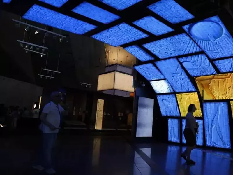 O vedere în întuneric, din interior, a Marelui Muzeu Egiptean, situat lângă Piramidele din Giza, în Giza, Egipt, pe 14 octombrie 2025. Sunt câțiva oameni în muzeul care găzduiește mii de artefacte din timpuri preistorice până în perioadele faraonice și romane