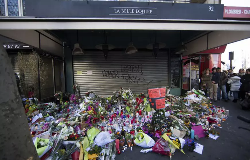 epa05026636 People lay flowers and candles in front of the Belle Equipe cafe in Paris, France, 15 November 2015. More than 120 people have been killed in a series of attacks in Paris on 13 November, according to French officials. Eight assailants were killed, seven when they detonated their explosive belts, and one when he was shot by officers, police said. French President Francois Hollande says that the attacks in Paris were an 'act of war' carried out by the Islamic State extremist group. EPA/IAN LANGSDON