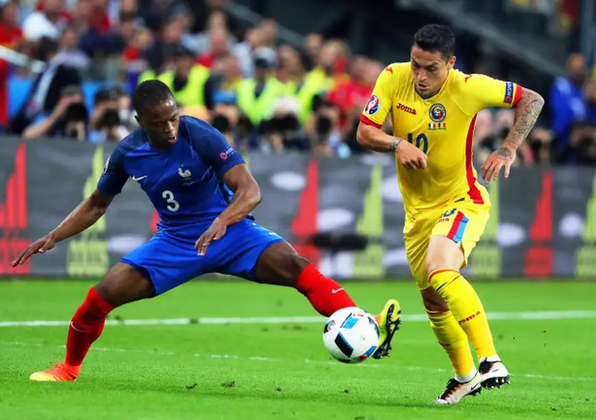 epa05355716 Romania's Nicolae Stanciu (R) in action against France's Patrice Evra (L) during the UEFA EURO 2016 group A preliminary round match between France and Romania at Stade de France in Saint-Denis, France, 10 June 2016. (RESTRICTIONS APPLY: For editorial news reporting purposes only. Not used for commercial or marketing purposes without prior written approval of UEFA. Images must appear as still images and must not emulate match action video footage. Photographs published in online publications (whether via the Internet or otherwise) shall have an interval of at least 20 seconds between the posting.) EPA/ABEDIN TAHERKENAREH EDITORIAL USE ONLY