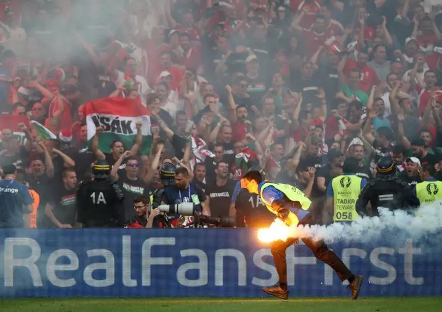 epa05375791 Ground staff remove a flare thrown onto the pitch by Hungarian supporters during the UEFA EURO 2016 group F preliminary round match between Iceland and Hungary at Stade Velodrome in Marseille, France, 18 June 2016. (RESTRICTIONS APPLY: For editorial news reporting purposes only. Not used for commercial or marketing purposes without prior written approval of UEFA. Images must appear as still images and must not emulate match action video footage. Photographs published in online publications (whether via the Internet or otherwise) shall have an interval of at least 20 seconds between the posting.) EPA/OLIVER WEIKEN EDITORIAL USE ONLY