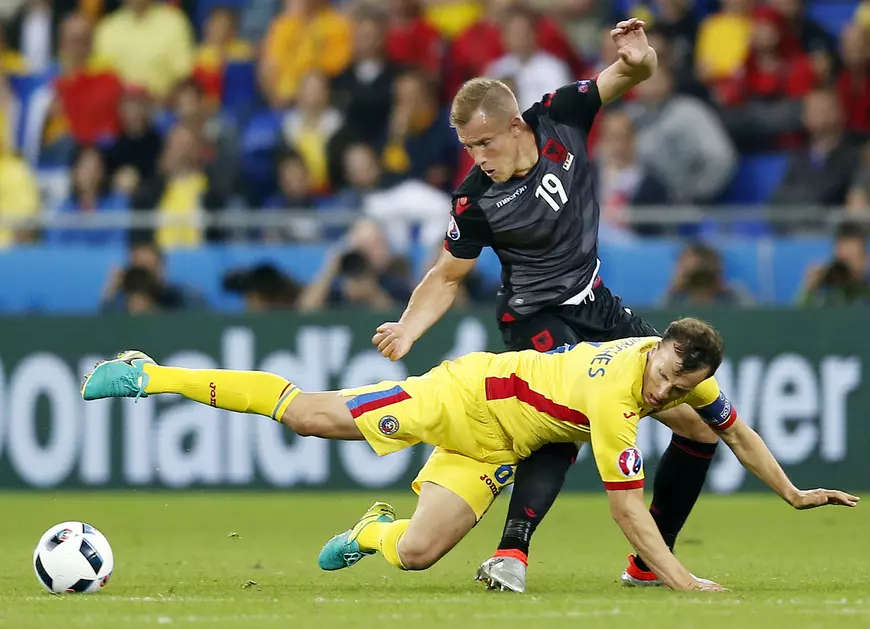 epa05378429 Vlad Chiriches of Romania in action against Bekim Balaj (standing) of Albania during the UEFA EURO 2016 group A preliminary round match between Romania and Albania at Stade de Lyon in Lyon, France, 19 June 2016. (RESTRICTIONS APPLY: For editorial news reporting purposes only. Not used for commercial or marketing purposes without prior written approval of UEFA. Images must appear as still images and must not emulate match action video footage. Photographs published in online publications (whether via the Internet or otherwise) shall have an interval of at least 20 seconds between the posting.) EPA/YURI KOCHETKOV EDITORIAL USE ONLY
