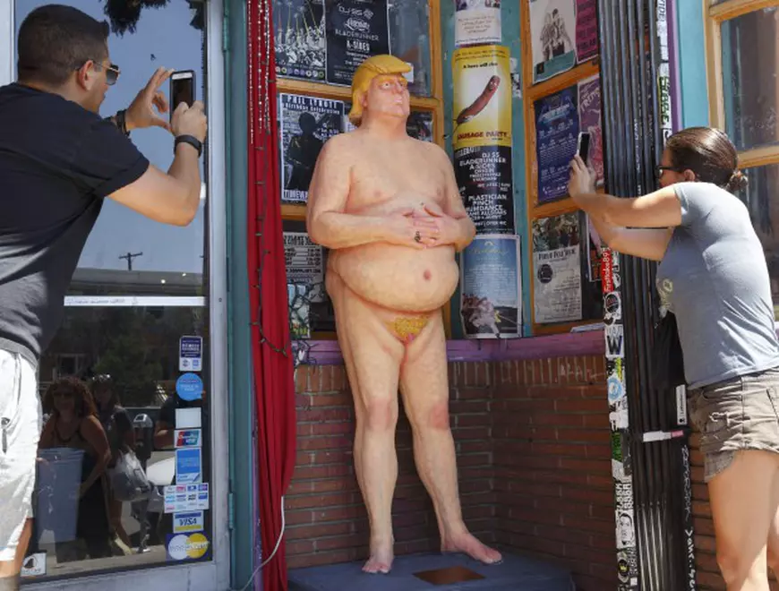 epa05497346 A naked Donald Trump statue gets the attention of passersby after being unveiled around the USA including in Los Angeles, California, USA, 18 August 2016. The unauthorized art installation was created by INDECLINE, a self-described anarchist group. The other cities where the statues appeared in the morning were San Francisco, Seattle, Cleveland and New York. EPA/EUGENE GARCIA