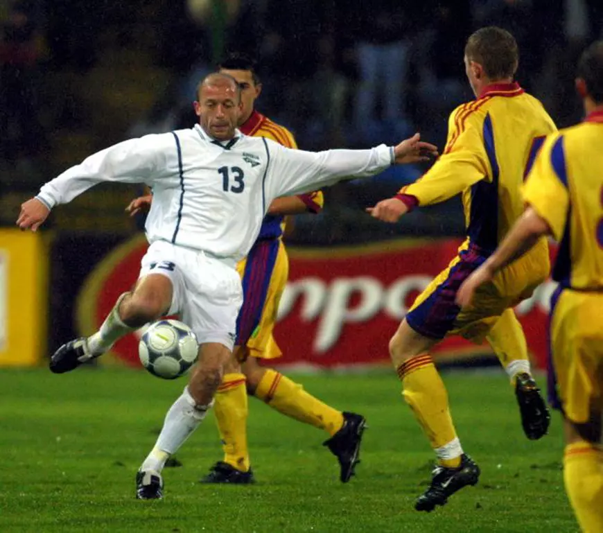 BUC13-20011114-BUCHAREST, ROMANIA: Slovenian player Mladen Rudonja (white) is challenged by the Romanian defence during the 2nd leg World Cup play-off in Bucharest on Wednesday, 14 September 2001. Rudonja scored his team's goal in the 1-1 draw tonight. Slovenia won 3-2 on aggregate and booked its place in next years World Cup finals. Behind Rudonja is Romania's Cosmin Contra. EPA PHOTO/ ROBERT GHEMENT