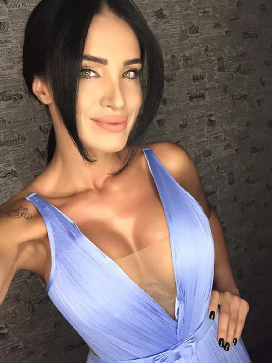 Adelina pestrițu pozează într-o rochie de culoare mov, cu un decolteu adânc