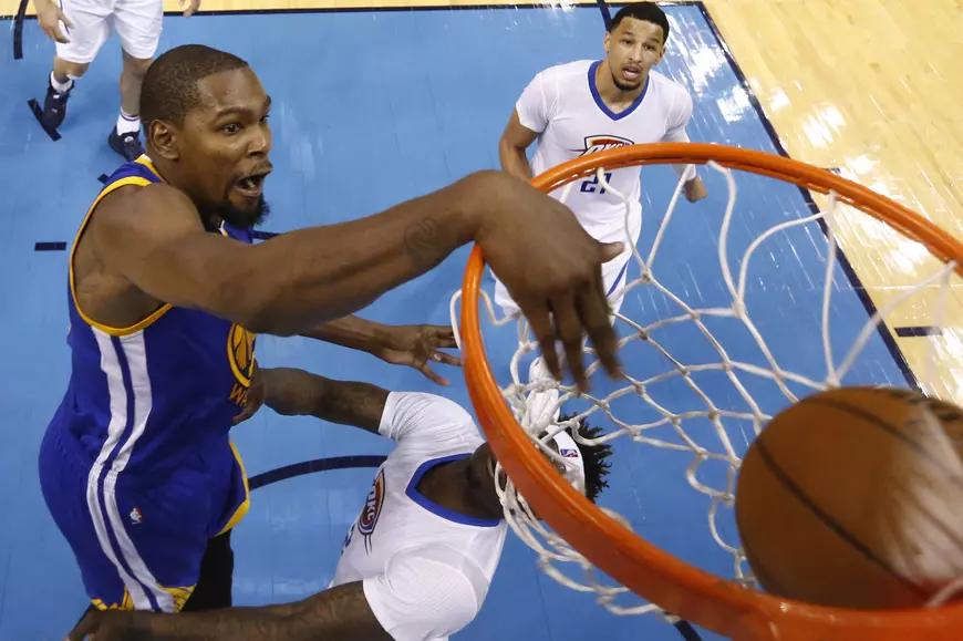 Kevin Durant (în albastru), baschetbalistul lui Golden State Warriors, marcând în timpul unui meci cu Oklahoma City Thunder. (FOTO: EPA)
