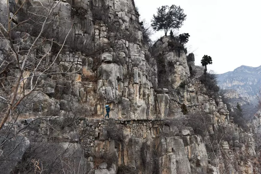 FOTO| La 60 de ani, un poștaș din China se cațără zilnic pe drumuri de munte pentru a livra ziare și scrisori