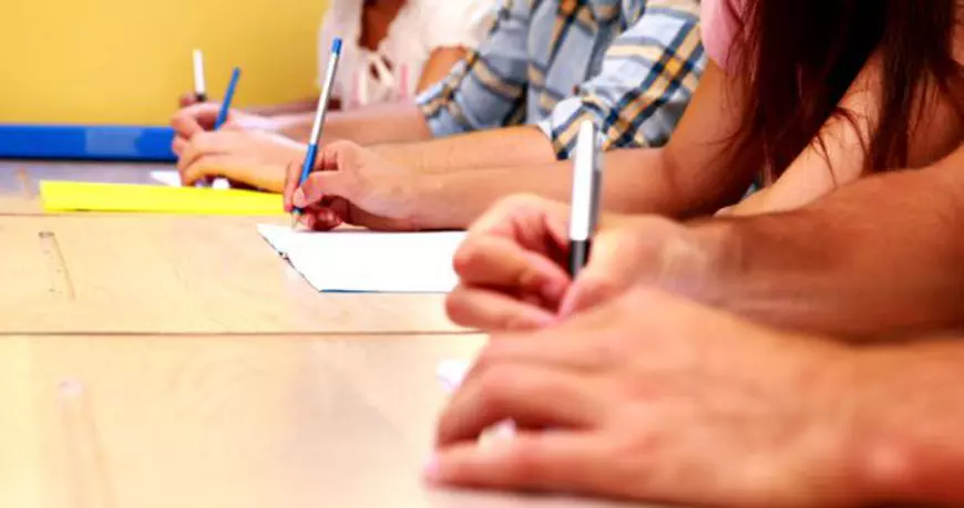 Bacalaureat 2018 - sesiunea specială pentru olimpici. Mai multe mâini de elevi, cu pixuri, în timpul unui examen