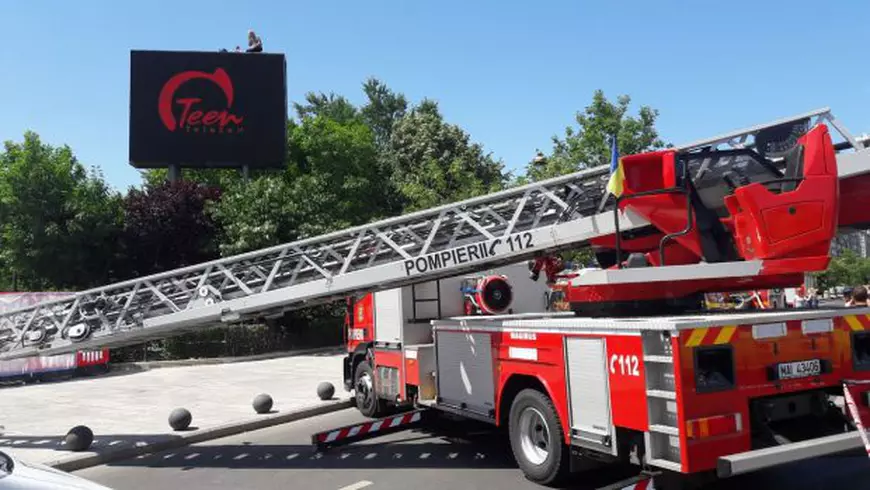 un bărbat amenință că se aruncă de pe un panou publicitar