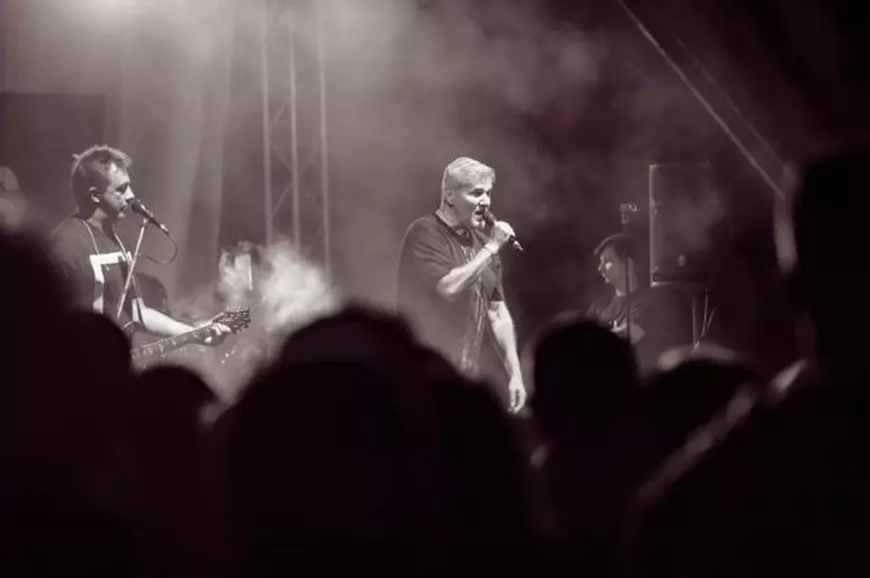 Trupa Holograf donează banii primiți pentru spectacolul din Sectorul 5. Fotografie alb-negru din timpul unui concert al trupei Holograf, cu Dan Bittman la microfon
