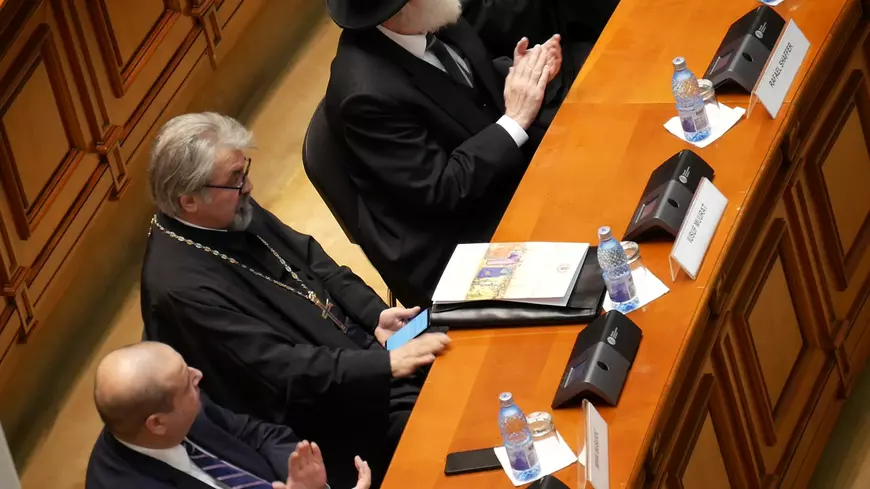 Un preot invitat în Parlament se uită pe telefon în timpul Şedinţei solemne de Centenar