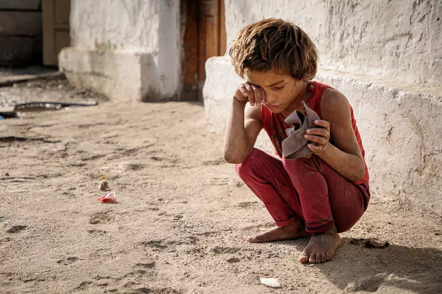 Un copil cu handicap stă retras de frații săi și o așteaptă pe mama lui să vină acasă.