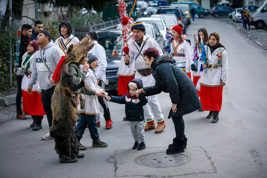 O femeie și nepoțelul ei s-au oprit să dea bani urătorilor