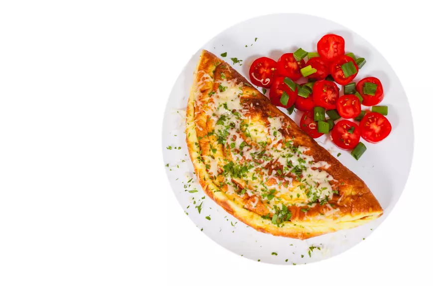 Omletă cu ceapă verde și roșii pe farfurie albă
