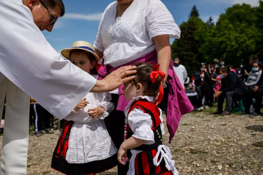 Două fetițe s-au emoționat la vederea preotului catolic ce împărțea credincioșilor pâine sfințită, Călugărul le-a mângâiat pe cap