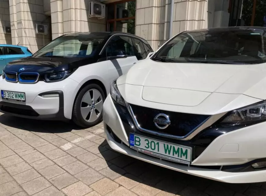 Numere de înmatriculare verzi - Imagine cu partea frontală a unor automobile electrice Nisan şi BMW, cu numere verzi.