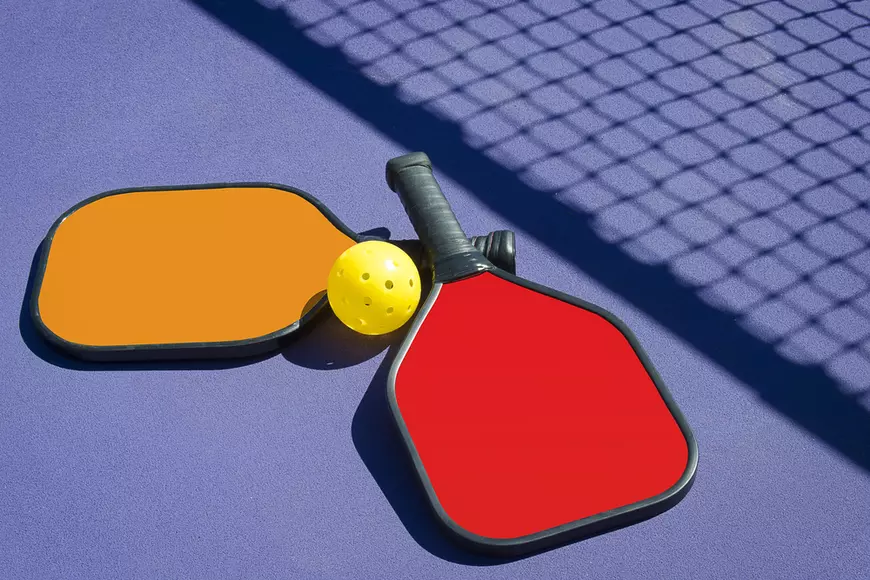 Ce este pickleball - Imagine cu două palete şi o minge de pickleball.
