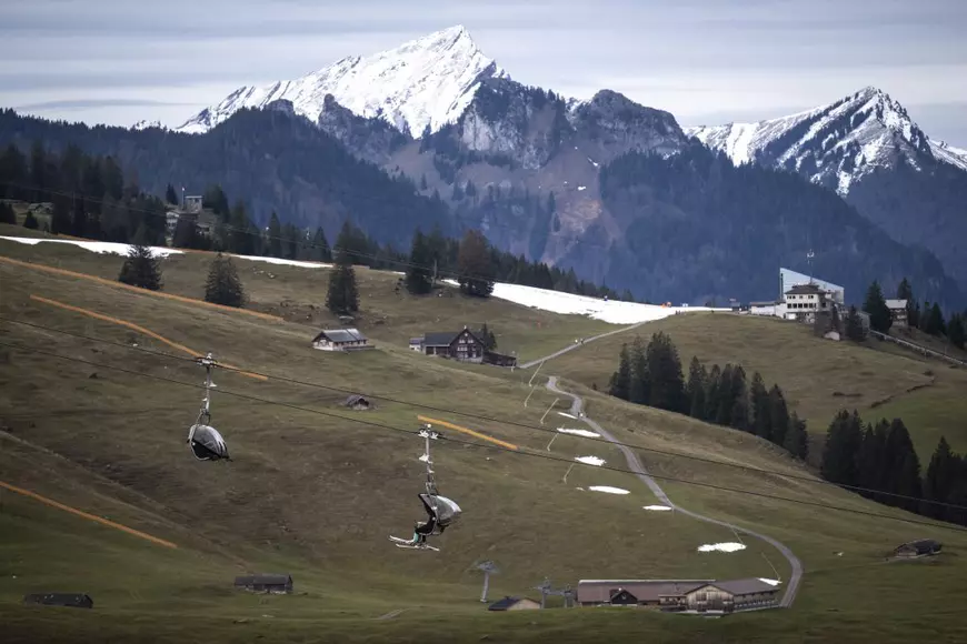 Footage from Switzerland of tourists walking in the mud on skis, the symbol of a snowless winter in Europe.  