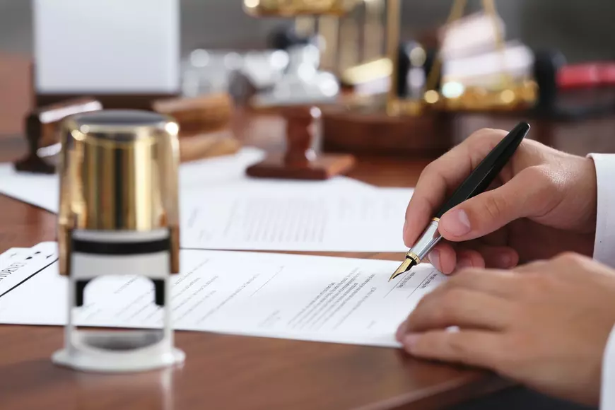 Ce face un notar – lista notarilor din București - Imagine cu un bărbat care semnează un document.