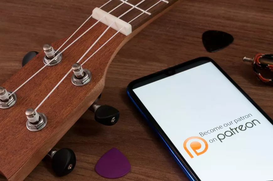 Reţele de socializare mai puţin cunoscute - Imagine cu ecranul de pornire al aplicaţiei Patreon, pe un telefon aflat lângă o chitară.