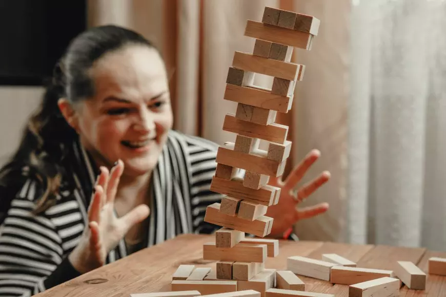 Cum se joacă Jenga - Imagine cu femeie care priveşte îngrijorată cum se prăbuşeşte un turn Jenga.