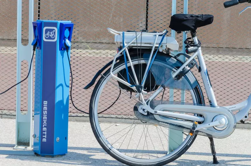 Cum să-ţi alegi bicicleta electrică potrivită - Imagine cu o bicicletă electrică aflată la o staţie de încărcare.