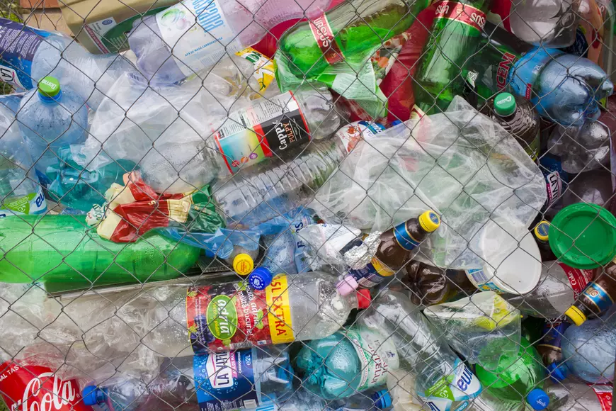 Cum funcţionează Sistemul de Garanţie-Returnare - Imagine cu numeroase deşeuri de palstic adunate lângă un gard de sârmă.