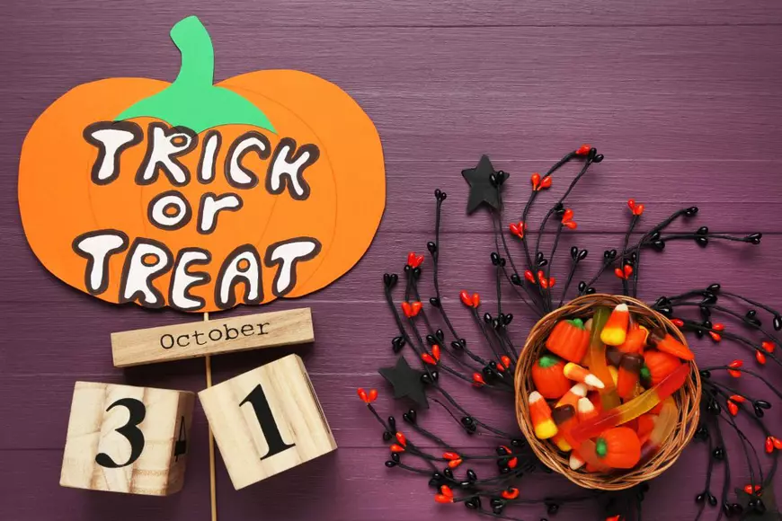 Când este Halloween 2024 – curiozități și tradiții - Imagine cu bomboane şi decoraţiuni de Halloween, între care se află un dovleac de hârtie pe care scrie Trick or Treat.