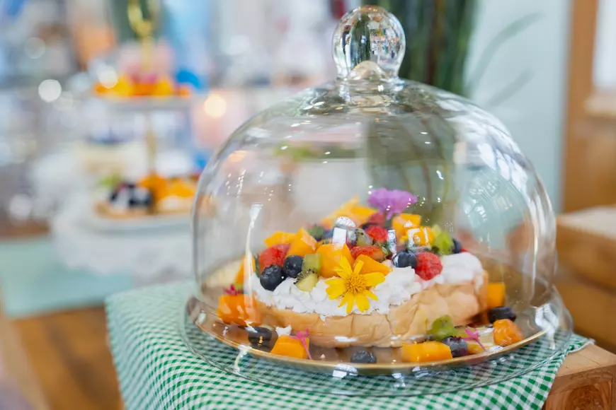 Flori comestibile - flori care pot fi folosite în preparate culinare - Imagine cu un preparat culinar ornat cu flori şi aşezat sub un bol de sticlă.